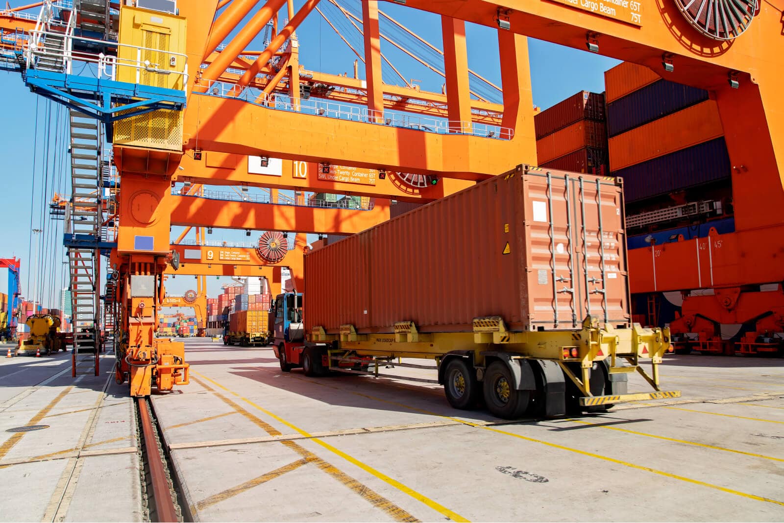 Large truck driving through a container ship yard.