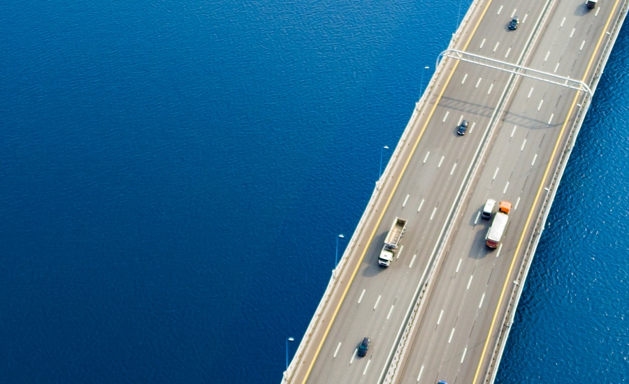 Overhead view of trucks and cars on a multilane bridge over water