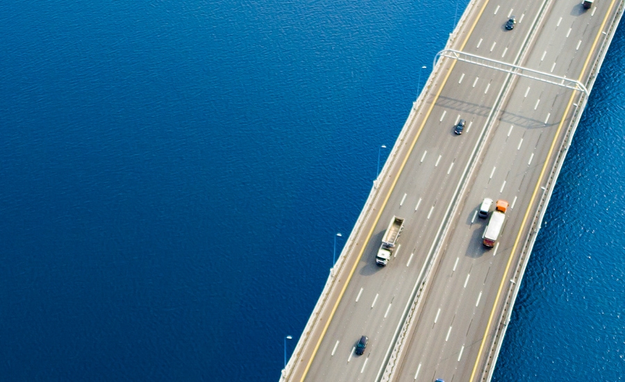 Bovenaanzicht van vrachtwagens en auto's op een meerbaansbrug over water