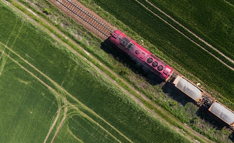 Overhead view of a cargo train going through green pastures